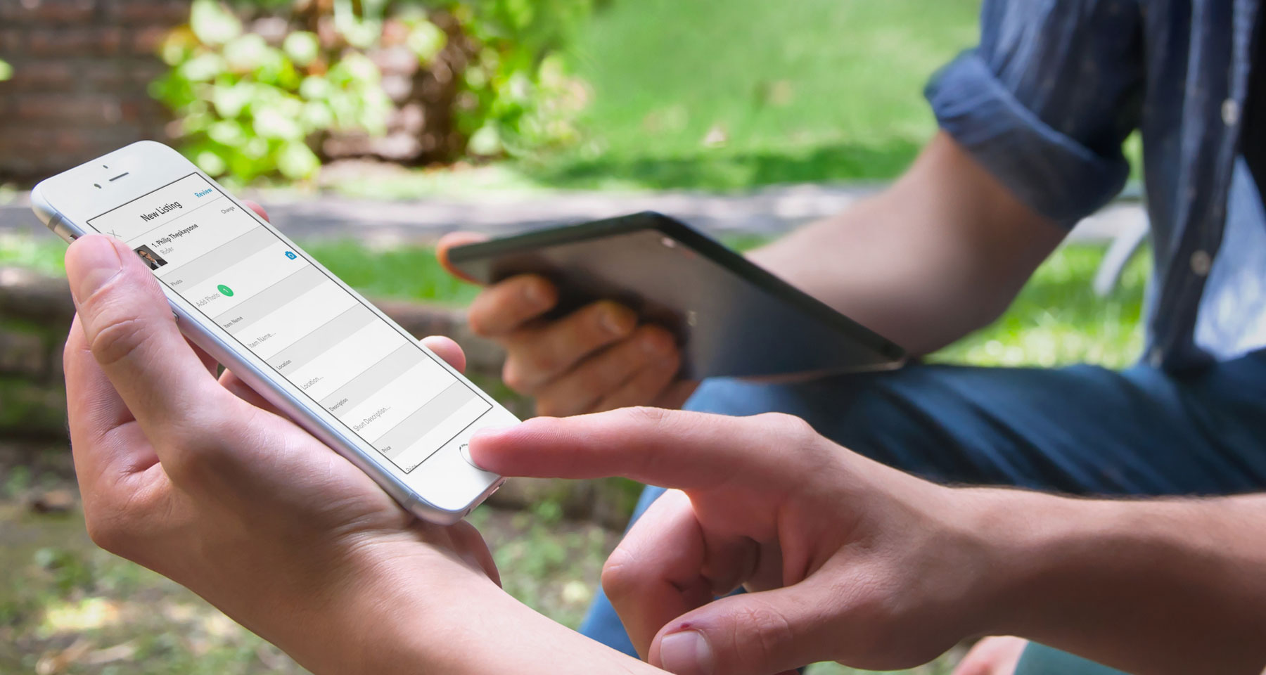 Two people outdoors, one filling in a "New Listing" form on an iPhone, the other holding a tablet