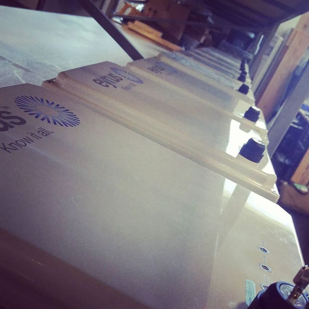 A row of white Eyrus enclosures seen at a low angle along a workshop shelf, each with a black cable gland and the "Know it all." logo