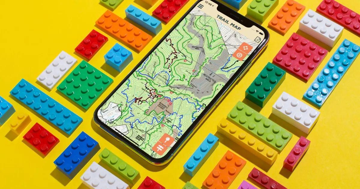 The Windrock Park trail map app on an iPhone, surrounded by Lego bricks.